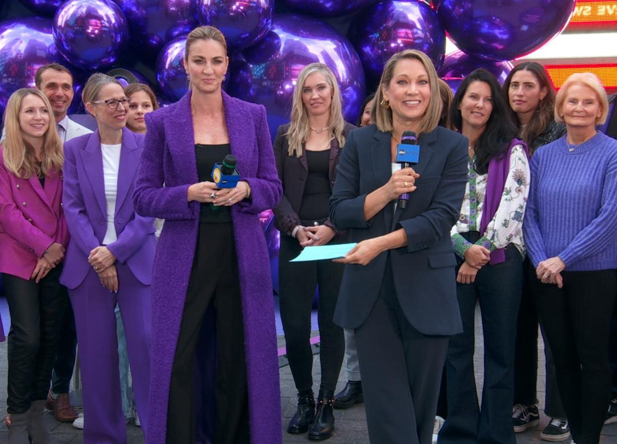 A group of women in purple suits and holding microphones.